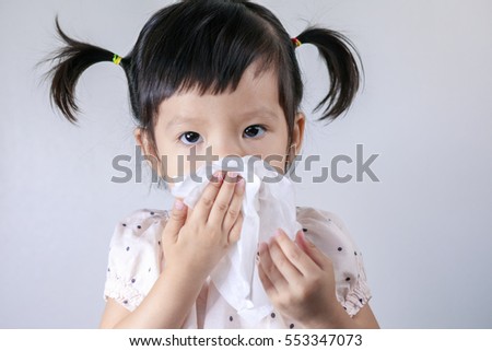 Little girl blowing his nose with tissue paper in the white background