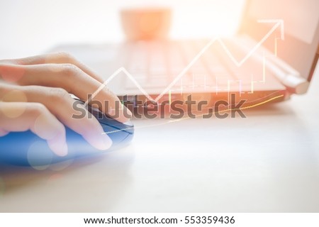 Business economic and technology working concept. Woman hand using mouse notebook double exposure graph money stock trading up trend green arrow bokeh background. Vintage tone filter effect color. 