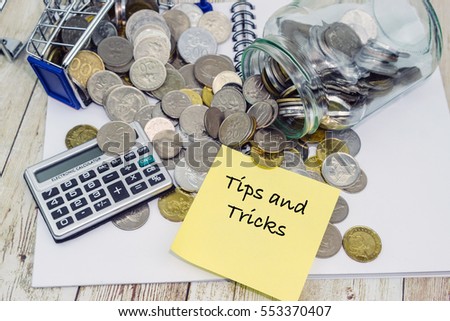 Shopping chart, coins, calculator and TIPS AND TRICKS wording on wooden table. Economy, financial, saving, debt concept