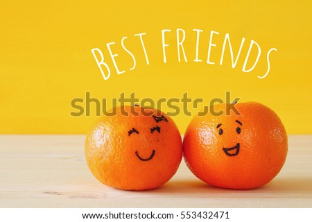 Image of two cute clementines with drawn smiley faces on wooden table. Best friend concept