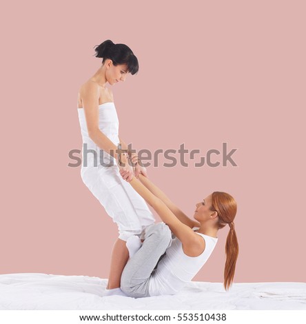 Young woman getting traditional Thai stretching massage by therapist over pink background