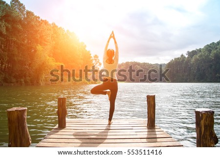 Healthy Yoga woman lifestyle balanced practicing meditate and energy yoga on the bridge in morning and sunset outdoors nature. Healthy life Concept
