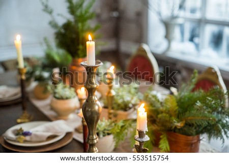 Festive table setting by candlelight, indoor. Winter decoration in rustic style.