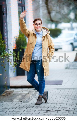 Young beautiful woman  in glasses, short fashionable hairstylein in office clothes, jacket, walking through the streets, spring walks