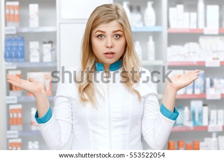 Lost and need help? Beautiful young female pharmacist looking confused and helpless gesturing with her hands drugstore help clueless doubtful confusion gesture expression specialist pharmacy concept Royalty-Free Stock Photo #553522054