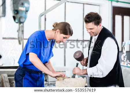 two Stonemasons carving pillar out of stone in workshop Royalty-Free Stock Photo #553557619