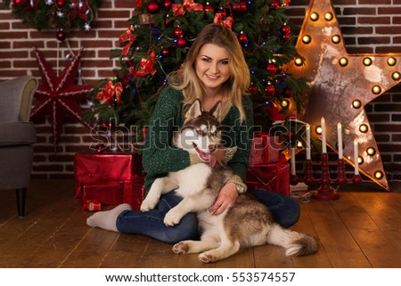 Girl hugging husky dog near Christmas tree