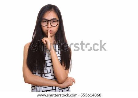Young Asian teenage nerd girl with finger on lips isolated against white background