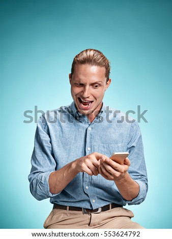 The young surprised caucasian businessman on blue background talking on cell phone