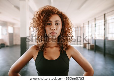 Portrait of beautiful afro american female with curly hair in gym. African fitness woman at healthclub. Royalty-Free Stock Photo #553660753