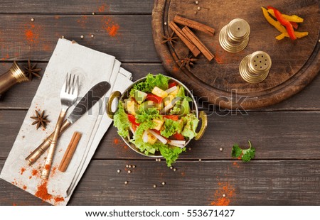 Vegan and vegetarian dish, fresh vegetable salad in copper bowl. Indian restaurant, lettuce and fruits mix with herbs, healthy meal, top view on wood background. Eastern local cuisine food.