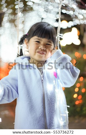 Portrait of a asia little girl with smile holding a Light bulbs with bokeh background. Kids and Christmas