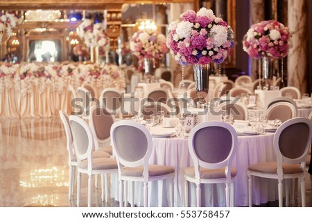 Grey chairs stand around dinner table number 8 in the hall Royalty-Free Stock Photo #553758457