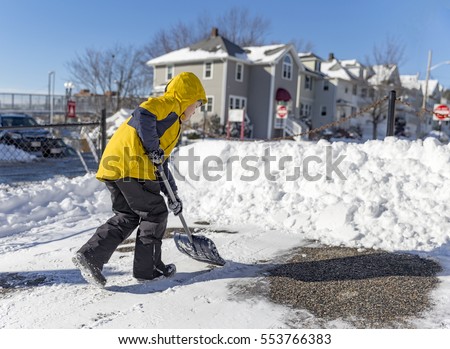 child cleans snow in the yard. boy shoveling snow. the concept of selfless assistance, citizen responsibility