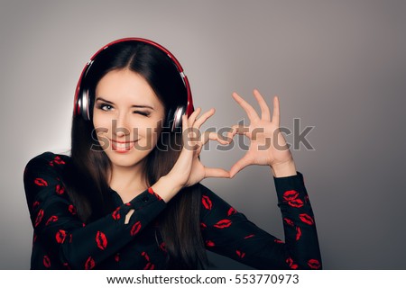 Smiling Girl with Headphones Making Heart Sign - Woman listening to a romantic love song dedication
