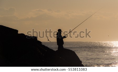 Fisherman silhouette while fishing at the pier in Sicily
