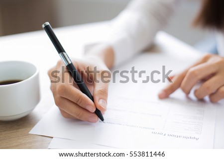 Closeup of Applicant Completing Application Form Royalty-Free Stock Photo #553811446