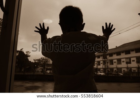 Boy standing and looking out through the mirror door Royalty-Free Stock Photo #553818604
