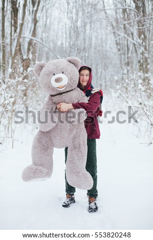 Man hold big teddy bear soft toy as a present to his girlfriend for birthday party in the winter