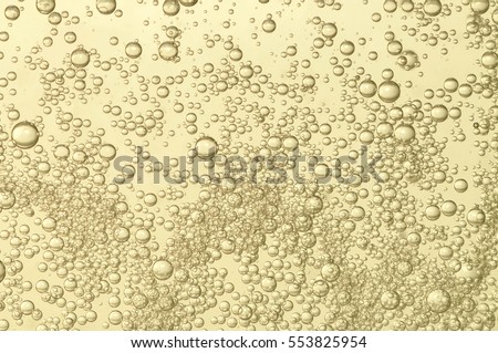Champagne fizz bubbles soars over a golden background Royalty-Free Stock Photo #553825954
