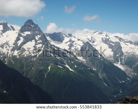 Snowy mountains and blue sky with clouds. Caucasus mountains.