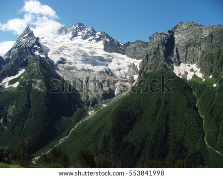 Snowy mountains and blue sky with clouds. Caucasus mountains.