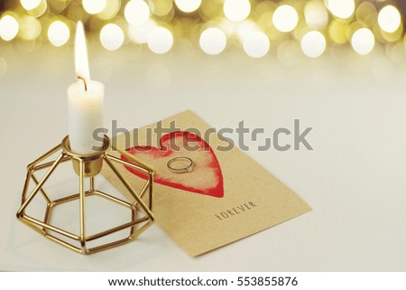 Engagement diamond ring on a card says Forever.  Candle in diamond  shaped candlestick. Space for your text