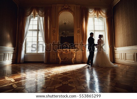 charming happy couple standing in a large palace