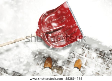 Man removing snow with the shovel from the backyard during the snowfall