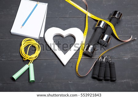 Heart, dumbbells, fitness background on a black wooden 