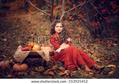 Cute girl with luxuriant hair sitting near truck with pumpkins. Boho fall style.