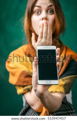 Surprised woman shows screen of smartphone.Mobile phone with black blank screen in focus