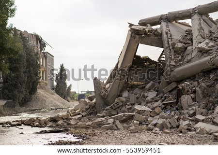 Industrial concrete building destructed by earthquake strike. Disaster scene full of debris, dust and crashed buildings. Royalty-Free Stock Photo #553959451