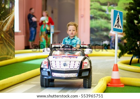 Little boy driving toy car on the traffic playground
