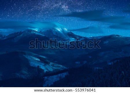 Starry sky with milky way in a sky above snow-capped peaks of the high mountain. Fantastic winter christmas night. The New Year's Eve.