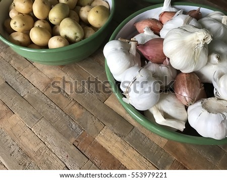 Garlic and onion in a green enamel bowl on a wooden table from different angles and close up and a bowl of potatoes