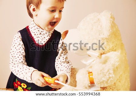 Girl playing doctor and treats teddy bear. Humorous photo  (Health, medicine, hospital)