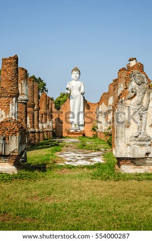 white statue of Buda standing among the ancient columns
