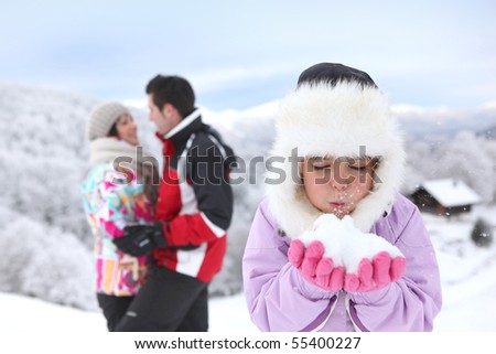 Portrait of a little girl in snowsuit blowing in snow