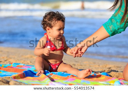 Baby girl on the beach seated on a towel