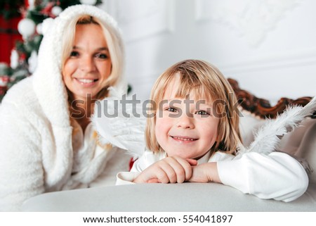 Portrait of happy mother and adorable baby celebrate Christmas. New Year's holidays. Toddler with mom in the festively decorated room with Christmas tree and decorations.