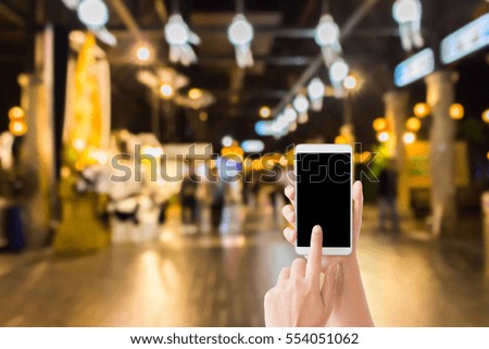 woman use mobile phone and blurred image of walkway in the night zoo with beautiful bokeh from the lights