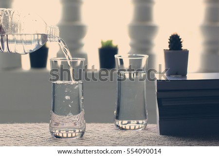 Pouring pure water from bottle into glass on table balcony in the room
