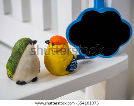 bird dolls made of stucco on white chair background with small board cloud , black space for insert text or image