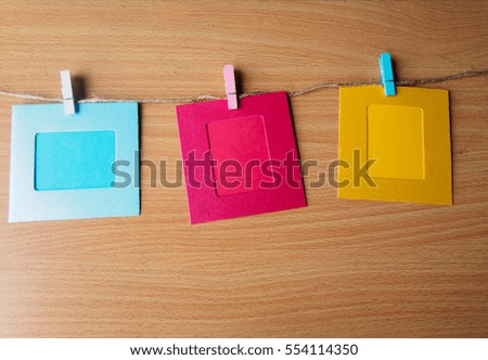 colorful picture frame hanging on the ropes with the peg on wooden wall background