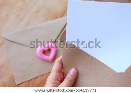 Blank white paper card with brown envelop over wooden background