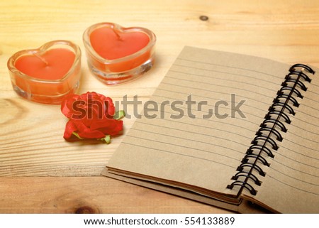 Recycle paper note book with red flower next  heart sign from candle in glass over wooden, Valentine's background and ecology concept ready to write text.