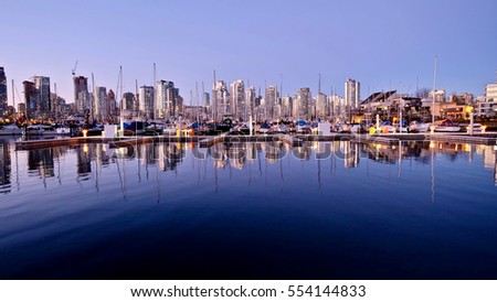 Reflections of city lights and boats in calm water. View of False Creek and Yaletown  from Kitsilano. Vancouver. British Columbia. Canada.