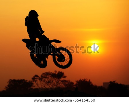 Motocroos rider jumping in sunset sky