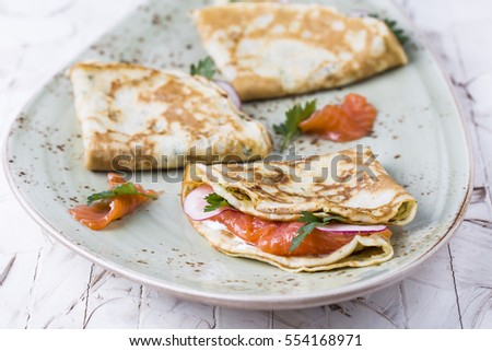 cheese pancakes with salmon, sour cream and herbs Royalty-Free Stock Photo #554168971